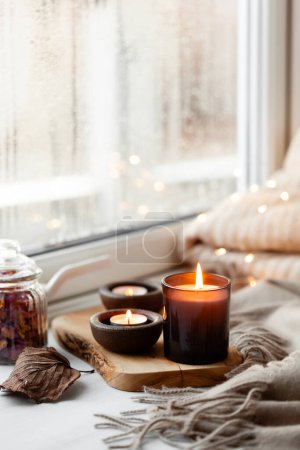warm cozy window arrangement, winter or autumn concept, candles throw lights
