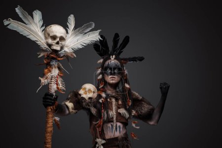 Foto de Disparo de bruja oscura vestida con ropa aborigen antigua sosteniendo al personal. - Imagen libre de derechos