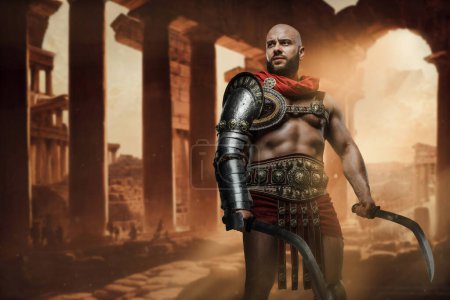 Téléchargez les photos : Prise de vue de gladiateur vêtu d'armure tenant deux épées sur des ruines abandonnées. - en image libre de droit