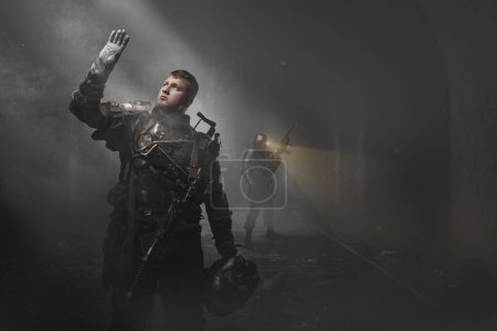 Téléchargez les photos : Portrait de survivant post-apocalyptique avec fusil de chasse regardant la lumière dans le métro poussiéreux. - en image libre de droit