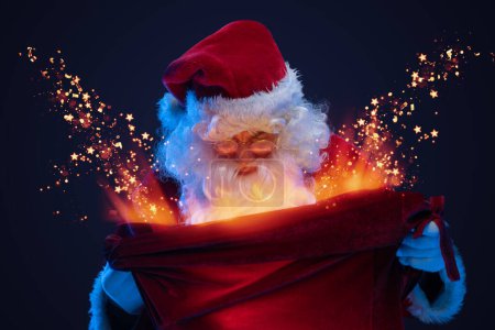 Téléchargez les photos : Prise de vue de Père Noël claus avec longue barbe regardant un énorme sac avec des cadeaux magiques. - en image libre de droit