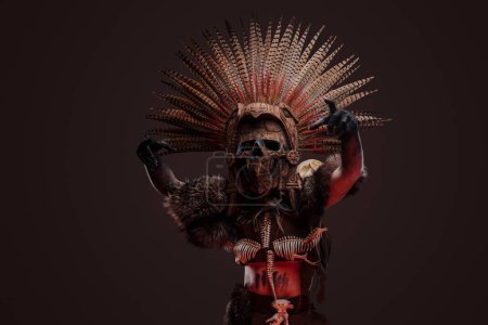 Foto de Tiro de espeluznante mujer zombi vestida con traje oscuro aborigen y tocado ceremonial. - Imagen libre de derechos