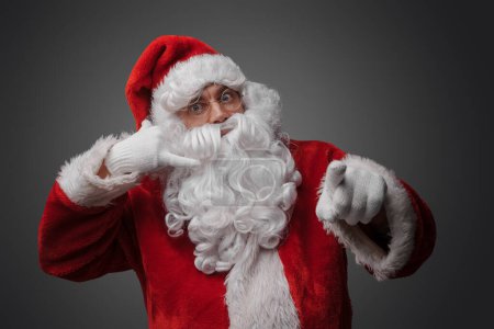 Photo for Studio shot of christmas santa with red suit and long beard pretending to talk on phone. - Royalty Free Image