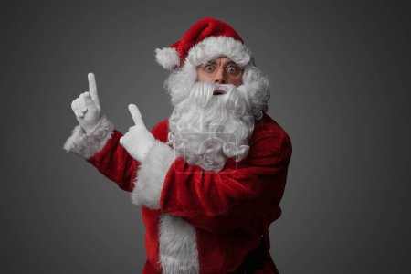 Téléchargez les photos : Portrait de vieux Père Noël vêtu d'un costume rouge pointant vers le haut. - en image libre de droit