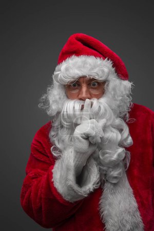 Photo for Shot of isolated on grey santa claus posing with finger at his lips. - Royalty Free Image