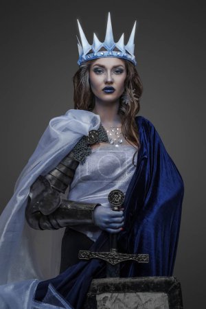 Téléchargez les photos : Prise de vue de la reine de glace guerrière avec épée et bouclier habillé en manteau et couronne. - en image libre de droit