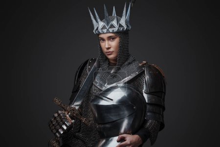 Foto de Foto de la valiente reina medieval vestida con armadura y corona sosteniendo la espada. - Imagen libre de derechos