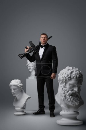 Téléchargez les photos : Plan studio d'un espion tenant un fusil sur son épaule autour de sculptures en marbre. - en image libre de droit