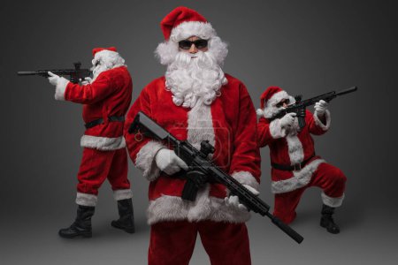 Photo for Studio shot of stylish crew of three santa with rifles isolated on grey background. - Royalty Free Image