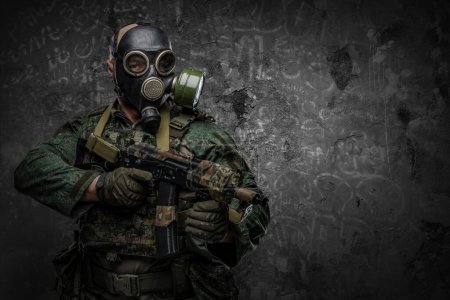 Foto de Shot of contemporary soldier with gas mask holding rifle against dark background. - Imagen libre de derechos
