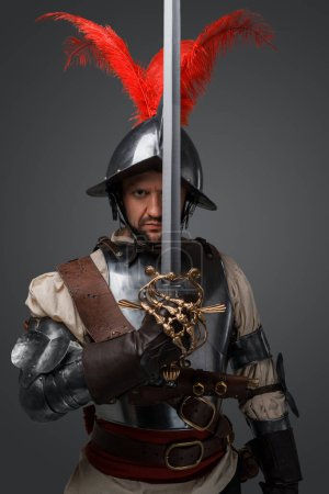 Téléchargez les photos : Studio shot of antique musketeer duelist with sword isolated on grey background. - en image libre de droit