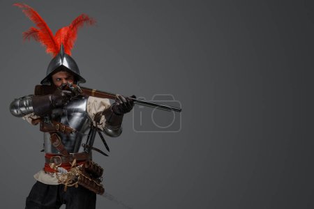 Photo for Studio shot of french rifleman dressed in plate armour aiming flintlock rifle. - Royalty Free Image