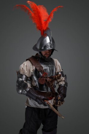 Photo for Studio shot of isolated on grey musketeer with sword and pistol dressed in armor. - Royalty Free Image