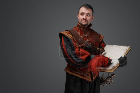 Photo for Portrait of musketeer duelist dressed in stylish suit holding book looking at camera. - Royalty Free Image