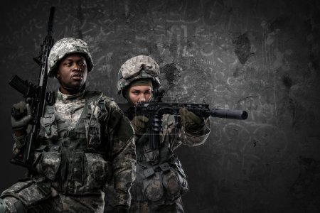 Photo for Studio shot of black soldier looking away and female comrade with rifle. - Royalty Free Image