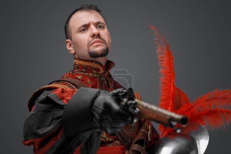 Foto de Portrait of conquistador with pistol dressed in red suit looking at camera. - Imagen libre de derechos