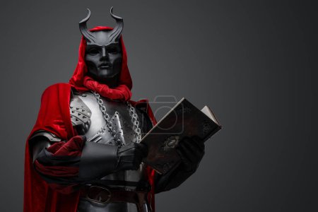Foto de Retrato de caballero malvado con libro vestido con túnica roja y armadura de placa. - Imagen libre de derechos