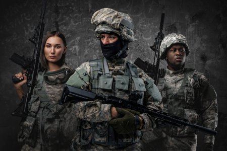 Photo for Shot of brave military people dressed in uniform holding rifles against gray background. - Royalty Free Image