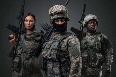 Photo for Shot of brave military people dressed in uniform holding rifles against gray background. - Royalty Free Image