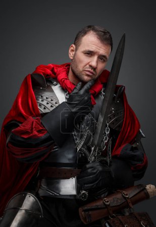 Photo for Studio shot of antique dark knight with steel armor and sword looking at camera. - Royalty Free Image