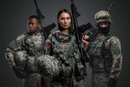 Foto de Portrait of team of three army soldiers dressed in camouflage suits holding rifles. - Imagen libre de derechos