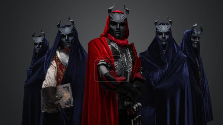 Téléchargez les photos : Portrait of four followers and their leader of dark cult dressed in dark robes. - en image libre de droit