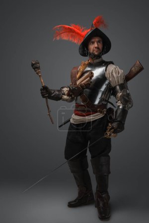 Foto de Retrato de conquistador medieval vestido con armadura de placas sosteniendo antorcha y espada. - Imagen libre de derechos