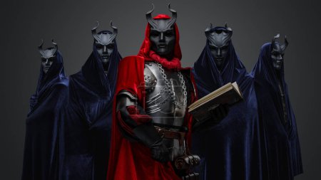 Téléchargez les photos : Portrait of dark cult members dressed in robes and their leader holding book. - en image libre de droit
