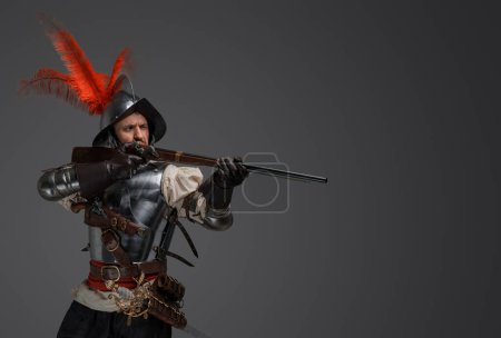 Photo for Studio shot of french rifleman dressed in plate armour aiming flintlock rifle. - Royalty Free Image