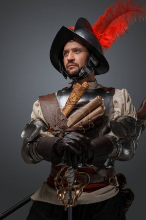 Foto de Shot of musketeer of renaissance period dressed in plate armor holding epee. - Imagen libre de derechos