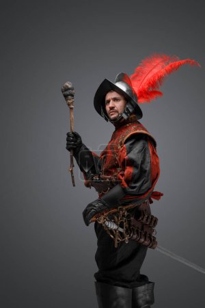 Foto de Shot of conquistador explorer dressed in plumed helmet and red attire holding torch. - Imagen libre de derechos