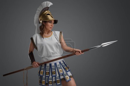 Téléchargez les photos : Prise de vue de combattante grecque antique avec casque doré et lance. - en image libre de droit