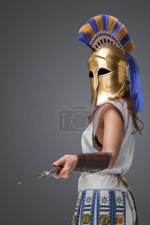 Foto de Portrait of greek female spearman dressed in light armor and golden helmet. - Imagen libre de derechos