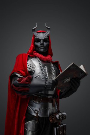 Photo for Studio shot of creepy dark cultist dressed in red robe holding book. - Royalty Free Image