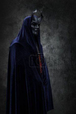 Téléchargez les photos : Shot of ancient cult prayer dressed in horned mask and dark robe. - en image libre de droit