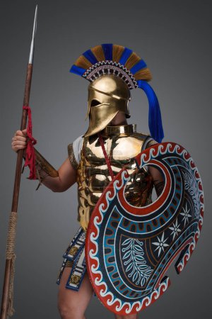 Téléchargez les photos : Portrait of isolated on grey background greek warrior dressed in bronze armor and helmet. - en image libre de droit