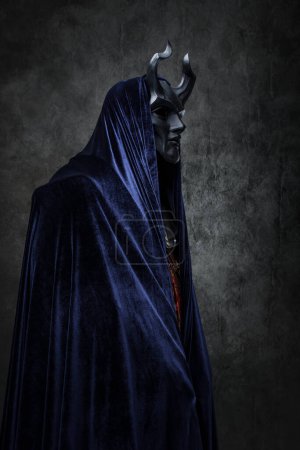Téléchargez les photos : Shot of ancient cult prayer dressed in horned mask and dark robe. - en image libre de droit