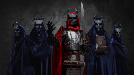 Foto de Disparo de cinco hermanos de culto místico vestidos con mantos oscuros y máscaras con cuernos. - Imagen libre de derechos
