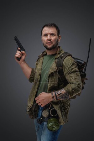 Téléchargez les photos : Shot of afraid guy with gun and backpack survived after post apocalypse. - en image libre de droit