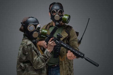 Téléchargez les photos : Shot of adult man and young girl in post apocalyptic style with gas masks and guns. - en image libre de droit