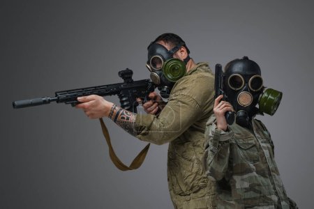 Photo for Shot of adult man and young girl in post apocalyptic style with gas masks and guns. - Royalty Free Image