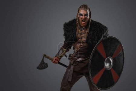 Téléchargez les photos : Prise de vue d'un barbare scandinave en colère vêtu d'une armure en cuir sur fond gris. - en image libre de droit