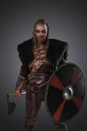 Téléchargez les photos : Portrait de viking médiéval avec bouclier et hache vêtu de fourrure noire. - en image libre de droit