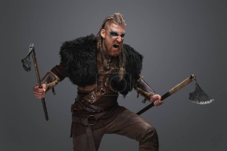 Photo for Portrait of crying viking with dual axes dressed in deerskin and armor. - Royalty Free Image