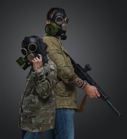 Foto de Tiro de hombre adulto y chica joven en estilo post apocalíptico con máscaras de gas y armas. - Imagen libre de derechos