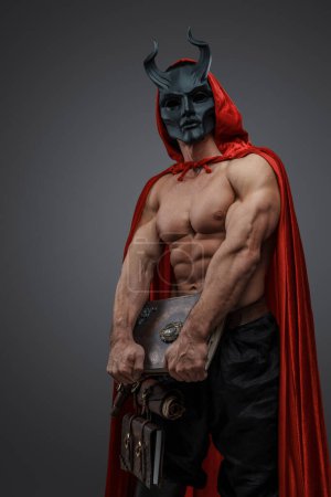 Foto de Tiro de brujo musculoso hombre de hermandad oscura vestido con manto rojo y máscara malvada. - Imagen libre de derechos