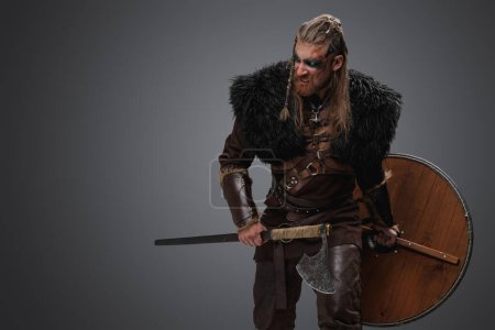 Portrait of violent barbarian from north with deerskin and armor against gray background.