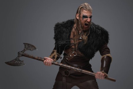 Shot of screaming nordic vandal dressed in leather armor and black fur with huge axe.