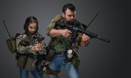 Foto de Retrato de adolescente post apocalíptica y chico con armas contra fondo gris. - Imagen libre de derechos