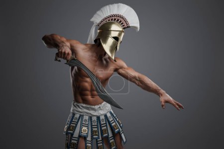 Téléchargez les photos : Prise de vue de guerrier topless de la Grèce avec un corps parfait sur fond gris. - en image libre de droit